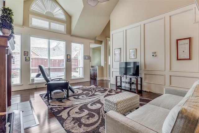 living area featuring a healthy amount of sunlight, high vaulted ceiling, a decorative wall, and hardwood / wood-style floors