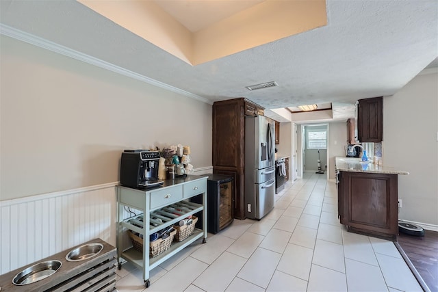 kitchen featuring stainless steel refrigerator with ice dispenser, visible vents, dark brown cabinetry, a textured ceiling, and range