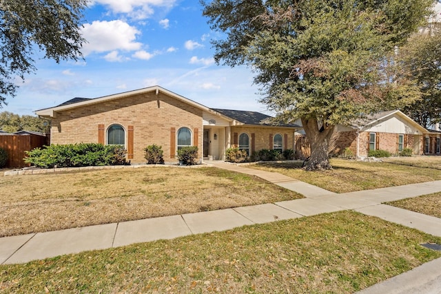 ranch-style house featuring brick siding, a front lawn, and fence