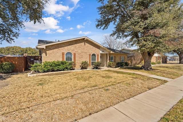 single story home featuring a front yard, brick siding, and fence