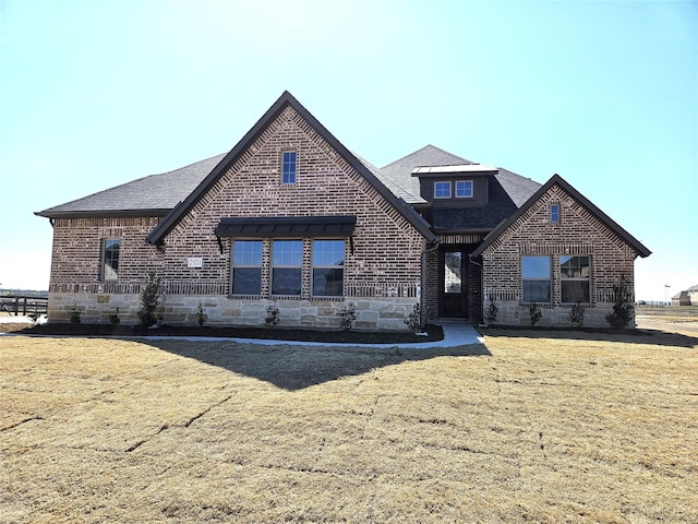 view of front of home with stone siding, a front yard, and brick siding