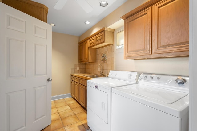 laundry room with light tile patterned floors, cabinet space, a sink, separate washer and dryer, and baseboards