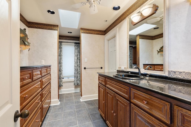 full bath with a skylight, baseboards, ceiling fan, tile patterned floors, and vanity