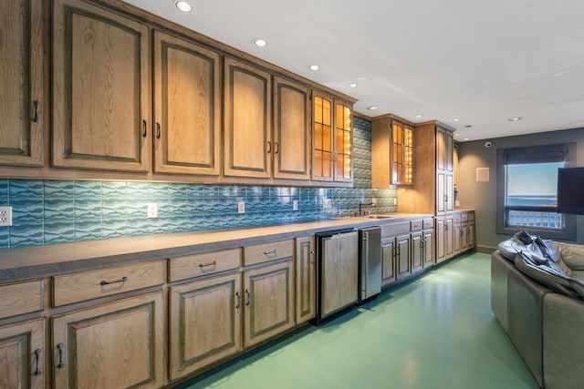 kitchen featuring recessed lighting, concrete floors, a sink, backsplash, and glass insert cabinets