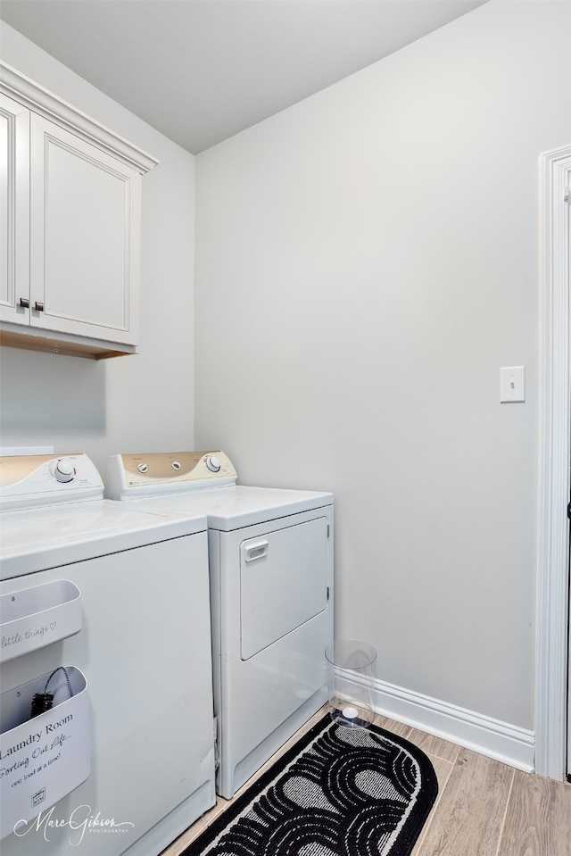 laundry room with wood finished floors, cabinet space, baseboards, and separate washer and dryer