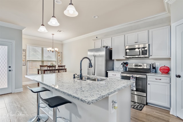 kitchen with a sink, visible vents, ornamental molding, appliances with stainless steel finishes, and wood tiled floor