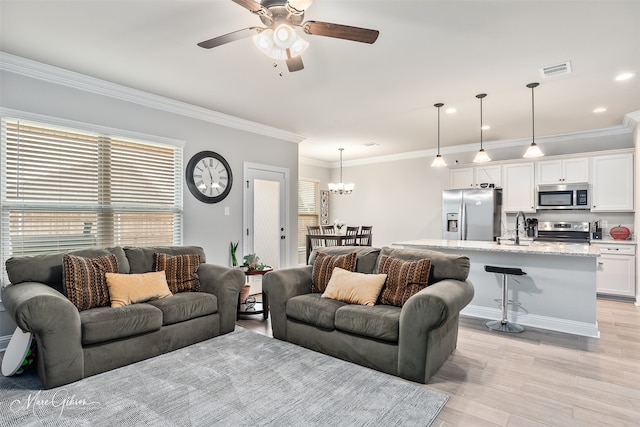 living area with visible vents, ceiling fan with notable chandelier, crown molding, light wood-style floors, and recessed lighting