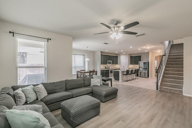 living room featuring visible vents, ceiling fan, stairs, light wood-type flooring, and recessed lighting