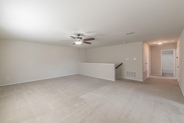 spare room featuring ceiling fan, visible vents, and light colored carpet