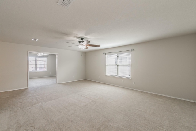 unfurnished room with light carpet, baseboards, visible vents, and a ceiling fan