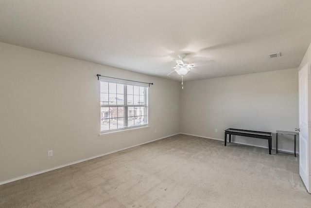 spare room featuring light carpet, ceiling fan, visible vents, and baseboards