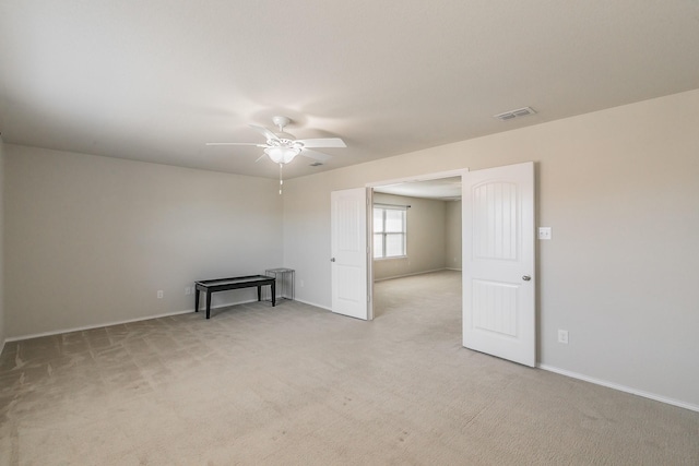 empty room featuring light carpet, visible vents, and a ceiling fan