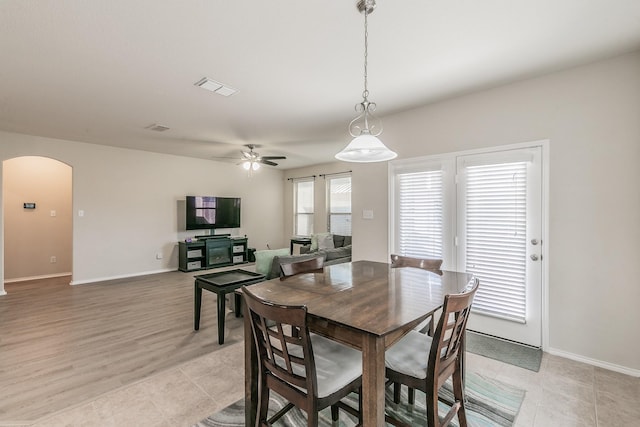 dining space with visible vents, arched walkways, ceiling fan, and baseboards