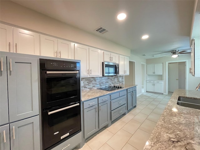 kitchen with light tile patterned floors, visible vents, decorative backsplash, a sink, and black appliances