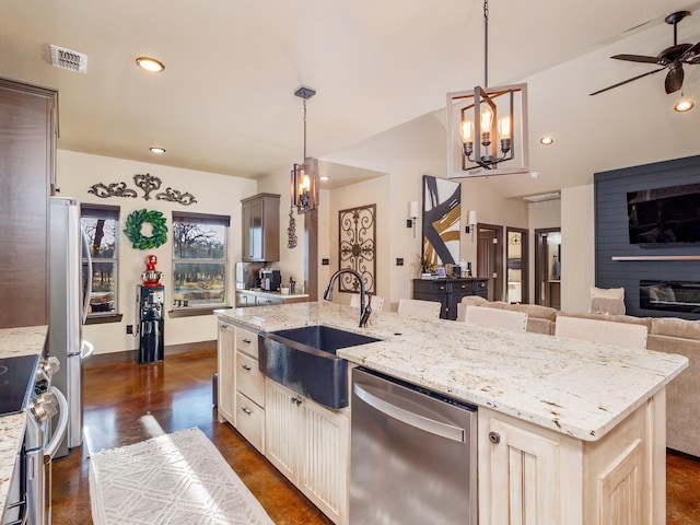 kitchen featuring stainless steel appliances, visible vents, open floor plan, a sink, and an island with sink