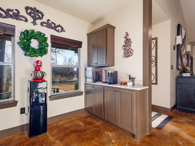 kitchen with baseboards, light stone countertops, and finished concrete floors