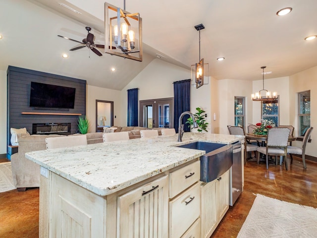 kitchen with dishwasher, light stone counters, open floor plan, a fireplace, and a sink