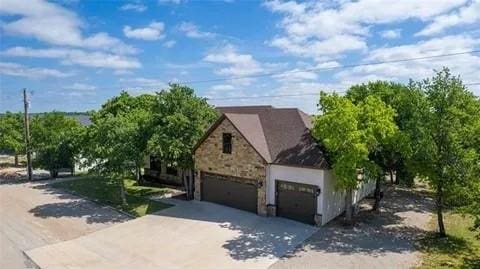 view of front of property featuring a garage, stone siding, and driveway