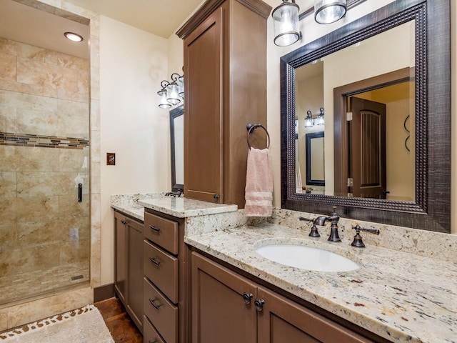 full bath featuring a shower stall, two vanities, and a sink