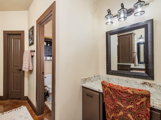 bathroom with toilet, vanity, and baseboards