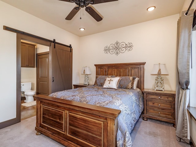 bedroom with recessed lighting, light colored carpet, ensuite bathroom, a barn door, and ceiling fan