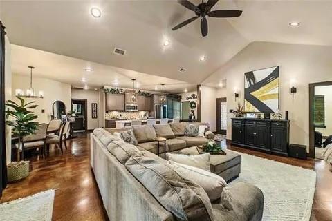 living room with lofted ceiling, recessed lighting, visible vents, baseboards, and ceiling fan with notable chandelier