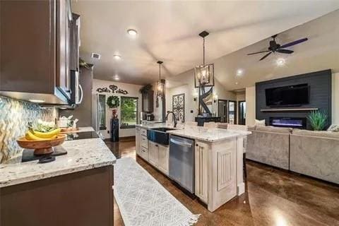 kitchen with decorative light fixtures, tasteful backsplash, a glass covered fireplace, a sink, and dishwasher