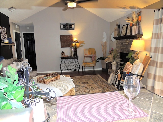 living room with lofted ceiling, visible vents, a stone fireplace, and baseboards