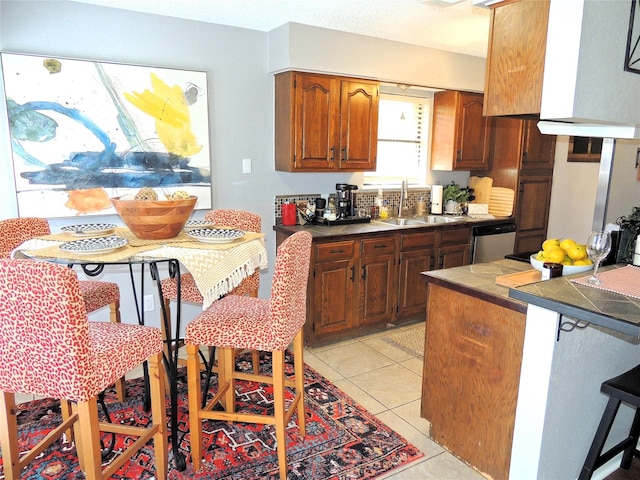 kitchen featuring tile countertops, brown cabinetry, light tile patterned flooring, a sink, and dishwasher