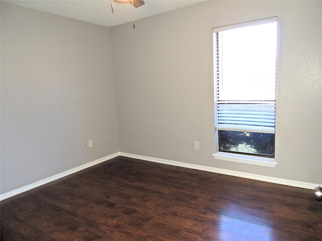 empty room featuring baseboards, dark wood finished floors, and a textured ceiling