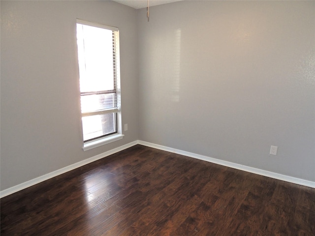 unfurnished room featuring dark wood-style flooring and baseboards