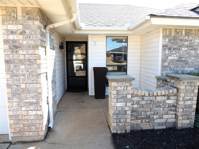 doorway to property with a shingled roof