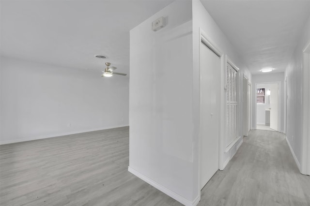 hall with light wood finished floors, visible vents, and baseboards