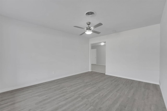 unfurnished room featuring a ceiling fan, visible vents, baseboards, and wood finished floors