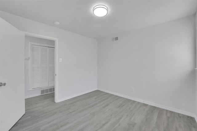 spare room with baseboards, visible vents, and wood finished floors