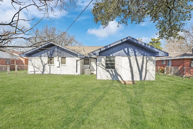 rear view of house featuring brick siding, a yard, and fence