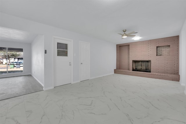 unfurnished living room featuring marble finish floor, a brick fireplace, a ceiling fan, and baseboards