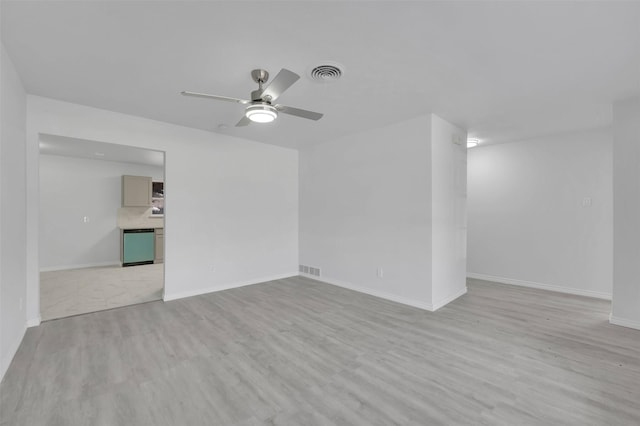 empty room featuring ceiling fan, light wood-style flooring, visible vents, and baseboards