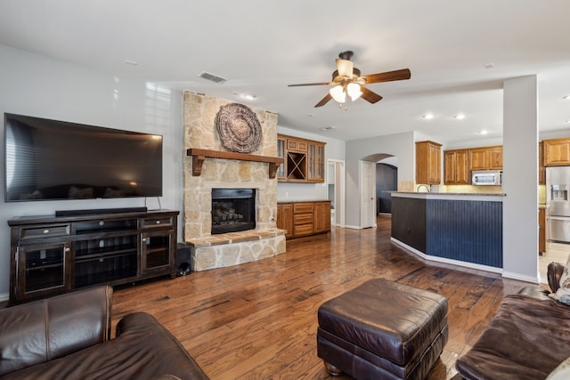 living room with wood finished floors, visible vents, arched walkways, and ceiling fan