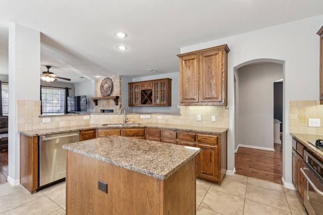 kitchen featuring ceiling fan, brown cabinetry, appliances with stainless steel finishes, and a sink