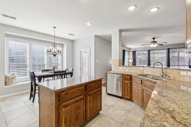 kitchen featuring light stone counters, decorative backsplash, stainless steel dishwasher, light tile patterned flooring, and a sink