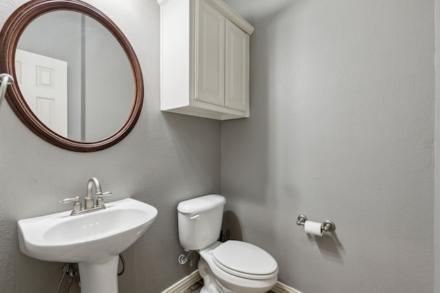 half bathroom featuring a sink, baseboards, and toilet