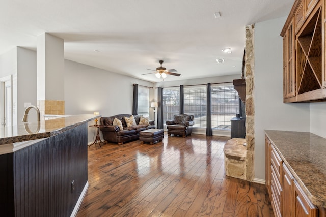 living room with baseboards, dark wood-style floors, visible vents, and ceiling fan