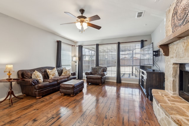 living area featuring visible vents, ceiling fan, a fireplace, and hardwood / wood-style flooring