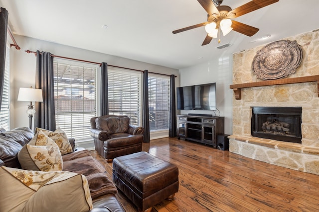 living area with visible vents, a fireplace, ceiling fan, and wood finished floors