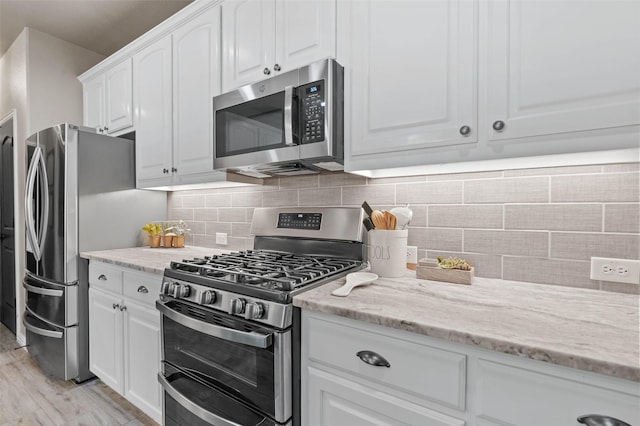 kitchen with light stone counters, appliances with stainless steel finishes, white cabinets, and tasteful backsplash