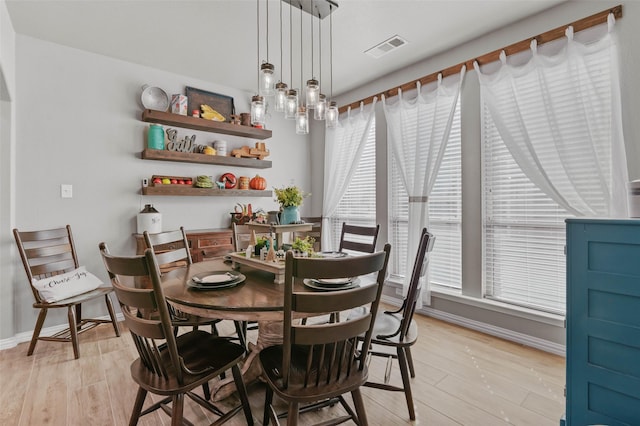 dining room with baseboards, visible vents, and light wood finished floors