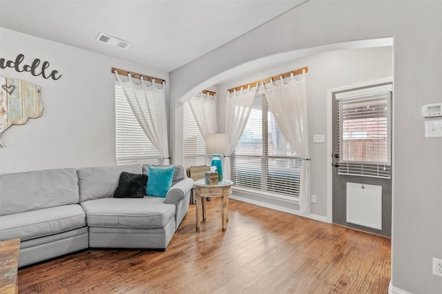 living area with baseboards, visible vents, and wood finished floors