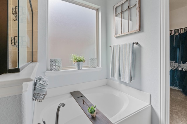 full bathroom featuring a garden tub, a spacious closet, and tiled shower