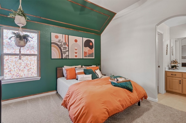 bedroom featuring light carpet, vaulted ceiling, arched walkways, and baseboards